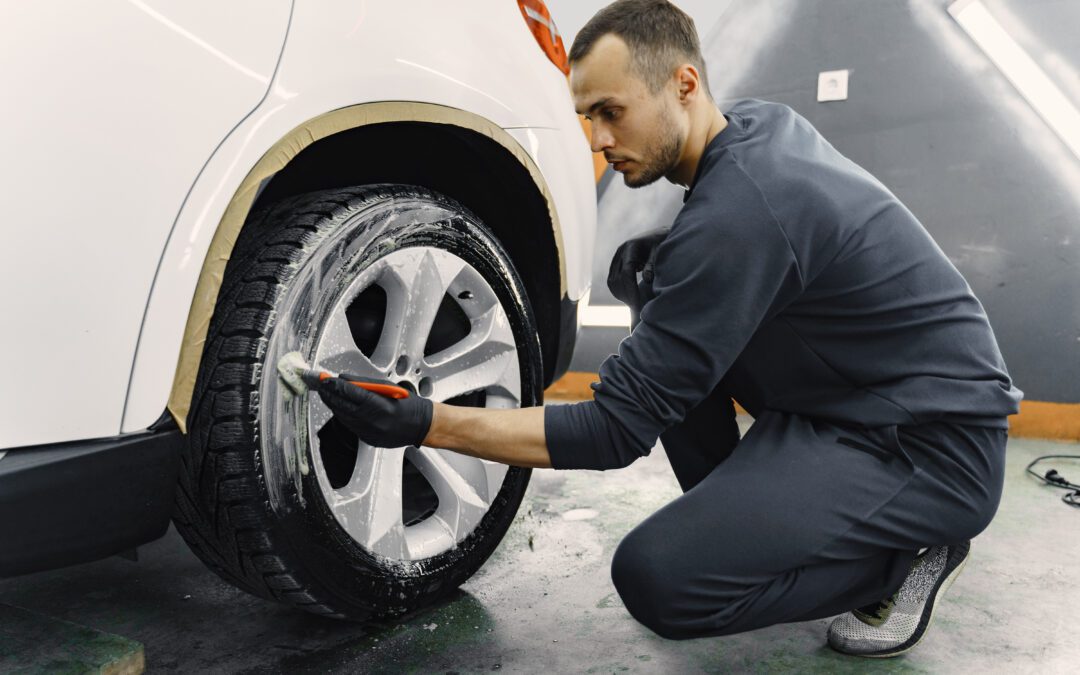 Men's hands are cleaning wheels. Hand of man holding sponge and foam washing wheel. Worker in a black uniform.